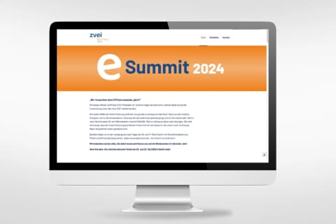eSummit-Website auf einem Monitor: Startseite mit orangem eSummit-Logo